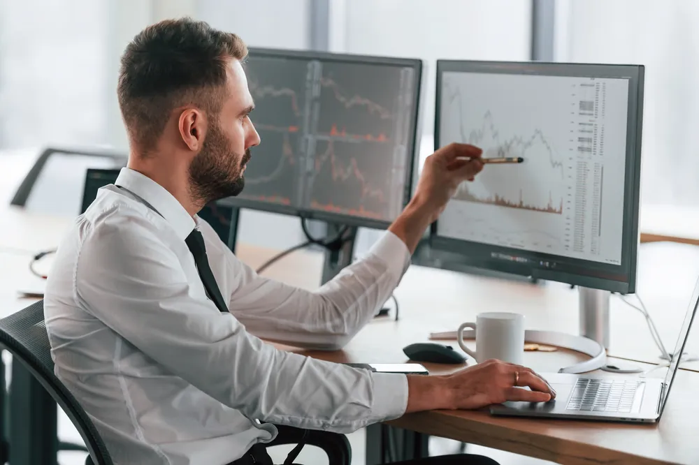 Dirigeant analysant des graphiques sur plusieurs écrans