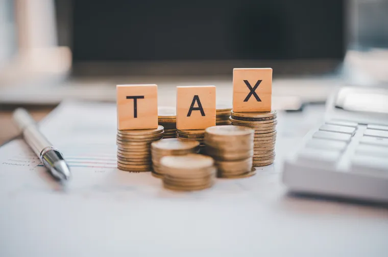 Cubes formant le mot TAX posés sur des pièces de monnaie